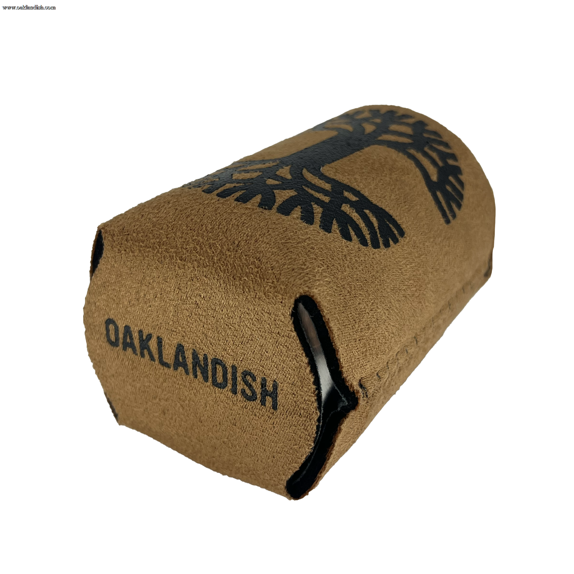 The Oaklandish Suede-ish Can Cooler is a brown can koozie branded with "OAKLANDISH" printed in black and accented by a black tree design above the text. The collapsible drink insulator sleeve, made of neoprene-like material, is positioned horizontally with its opening facing the left side of the image.