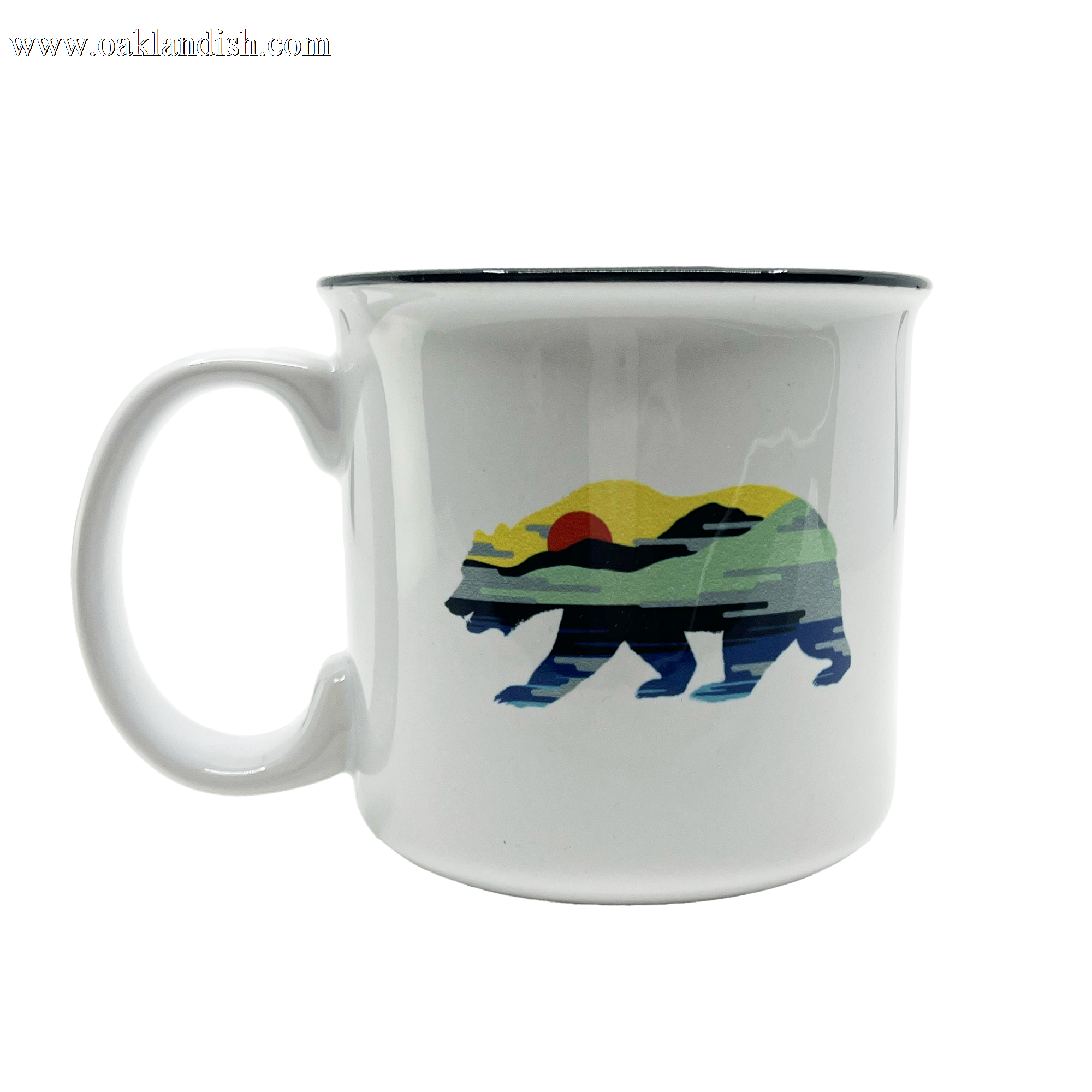 Introducing the Sunset Bear Coffee Mug by Oaklandish, a white ceramic mug adorned with a vibrant California grizzly design. The bear is filled with a captivating landscape scene featuring a red sun, green and yellow hills, and a blue sky. It is elegantly accented with a black rim and sturdy handle against its plain white background.