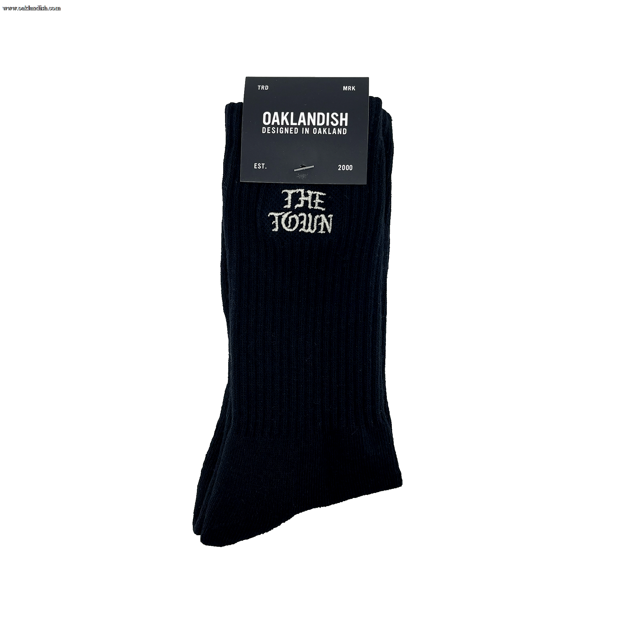 The Town Old English Sock, designed by Oaklandish, is a pair of black crew socks featuring "THE TOWN" embroidered in white lettering near the top. The packaging includes a black label with "OAKLANDISH DESIGNED IN OAKLAND," the Nike logo, and additional text stating "FOR MEN," "ONE SIZE FITS MOST," and "EST. 2000.